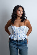 Mujer luciendo el Corset Valeska con estampado floral, copas estructuradas, tirantes delgados y ruedo con volantes peplum.