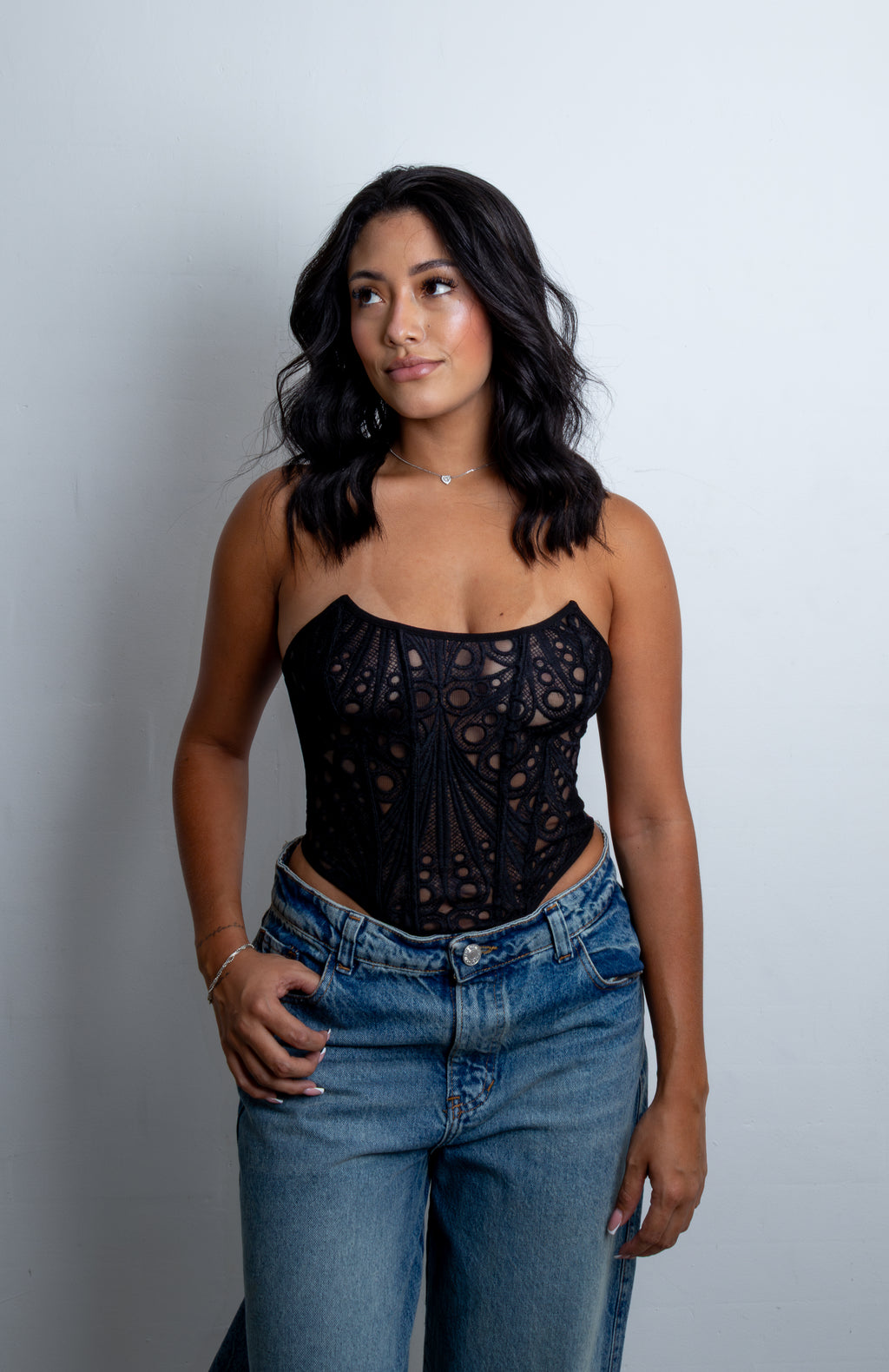 Mujer luciendo el Corset Leonor strapless en encaje bordado sobre malla, con varillas visibles y corte en V en la cintura.