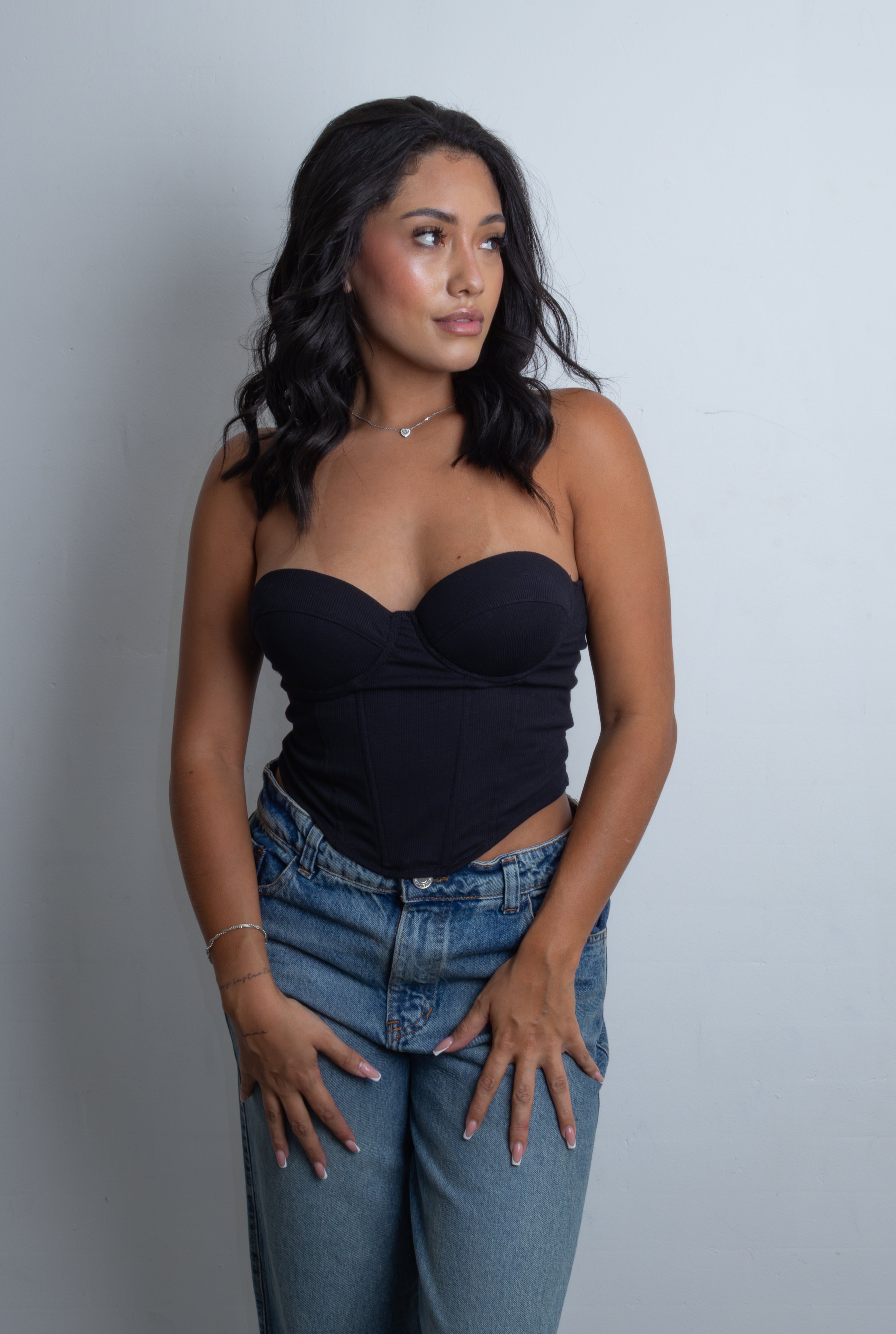 Mujer posando con el Corset Amanda strapless en tejido acanalado con copas preformadas y corte en pico en la cintura.