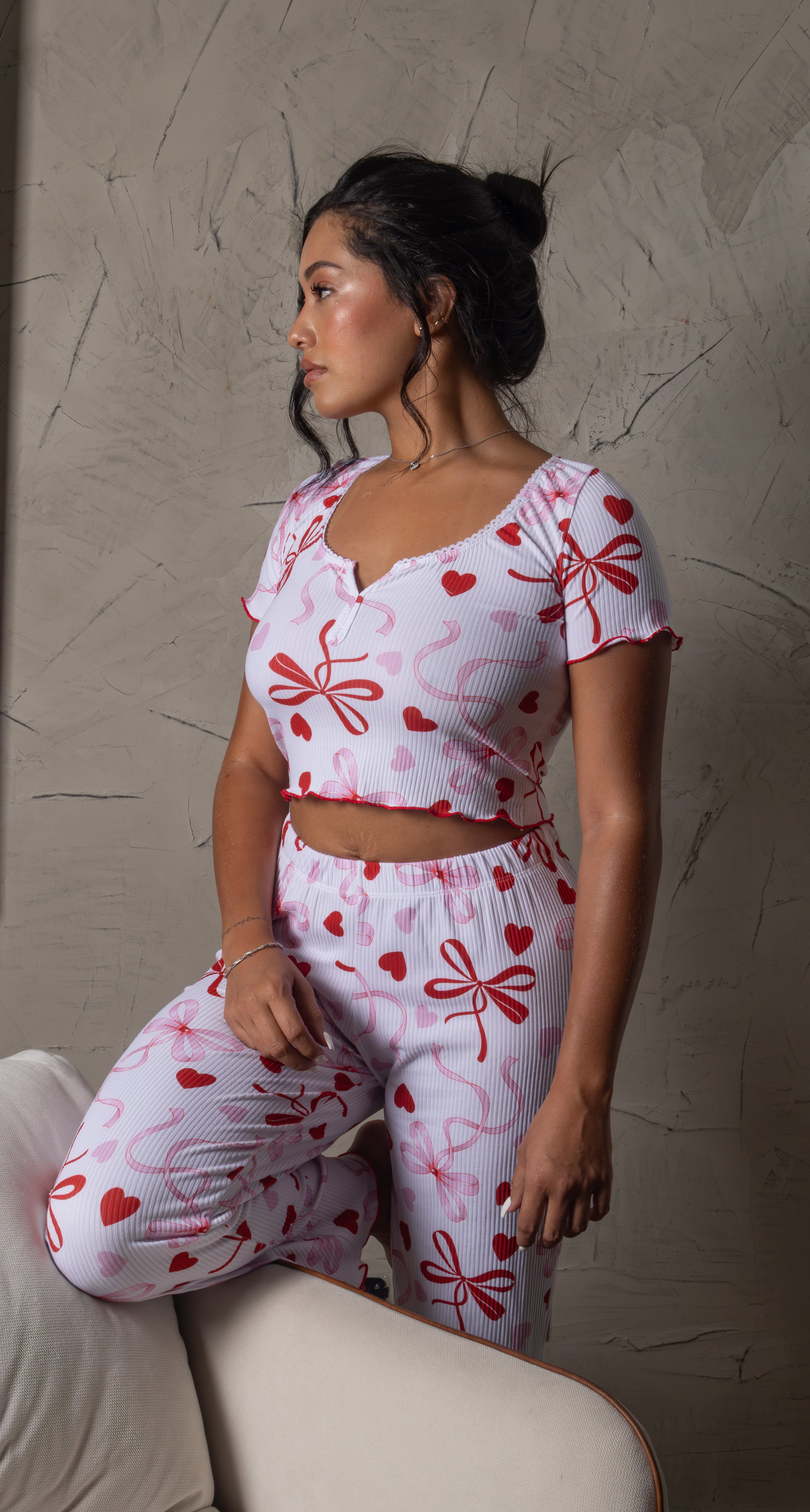 El Pijama Melisande combina un diseño divertido y femenino con el confort que buscas para tus momentos de descanso. Su base blanca de textura acanalada está decorada con estampados de Hello Kitty, moños y detalles en rojo y azul. Incluye un top de manga corta con botones frontales y pantalón largo a juego, creando un conjunto ideal para relajarte con mucho estilo.