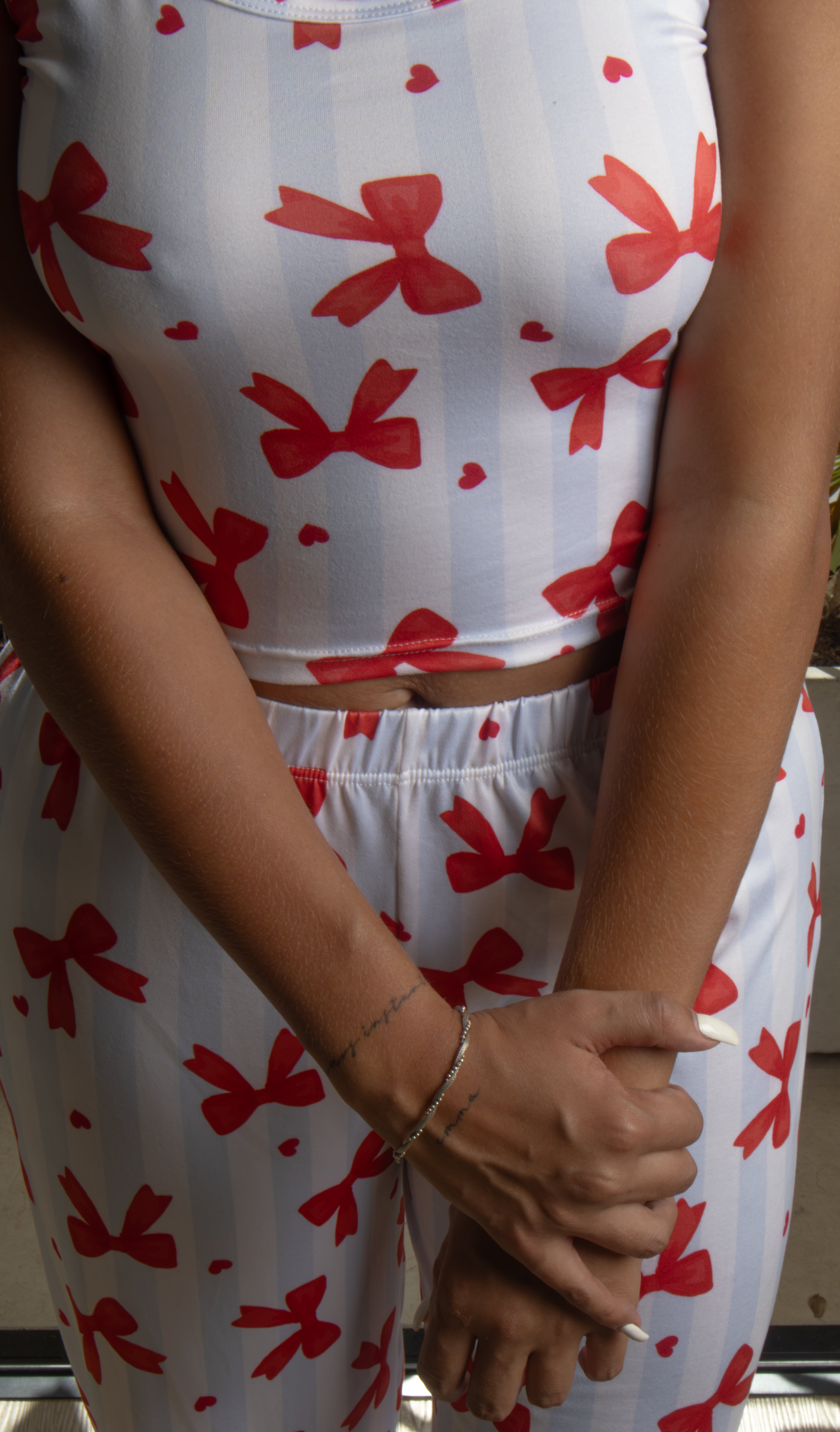 El Pijama Nadine destaca por su diseño femenino, fresco y encantador. Su estampado de moños rojos sobre fondo blanco crea un look romántico y moderno, mientras que el conjunto de top corto y pantalón largo ofrece una silueta cómoda y ligera. Perfecto para descansar, relajarte en casa o disfrutar de tus momentos de autocuidado con estilo.