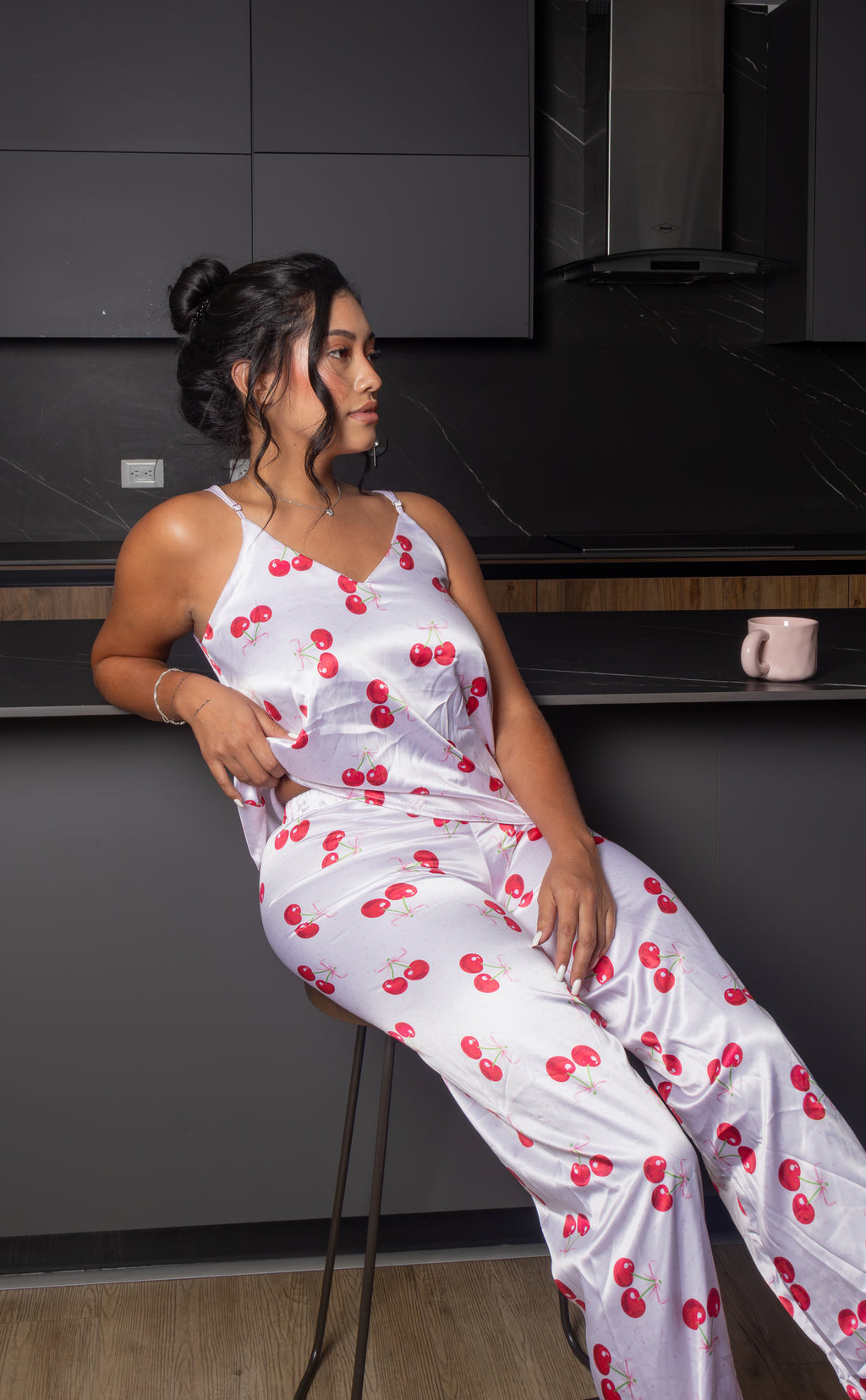 Dale un toque dulce y femenino a tus noches con la Pijama Jolie, un conjunto de dos piezas con acabado satinado y delicado estampado de cerezas. Su top de tirantes ajustables y pantalón de pierna amplia crean una silueta cómoda, fresca y estilizada, perfecta para descansar con mucho estilo.