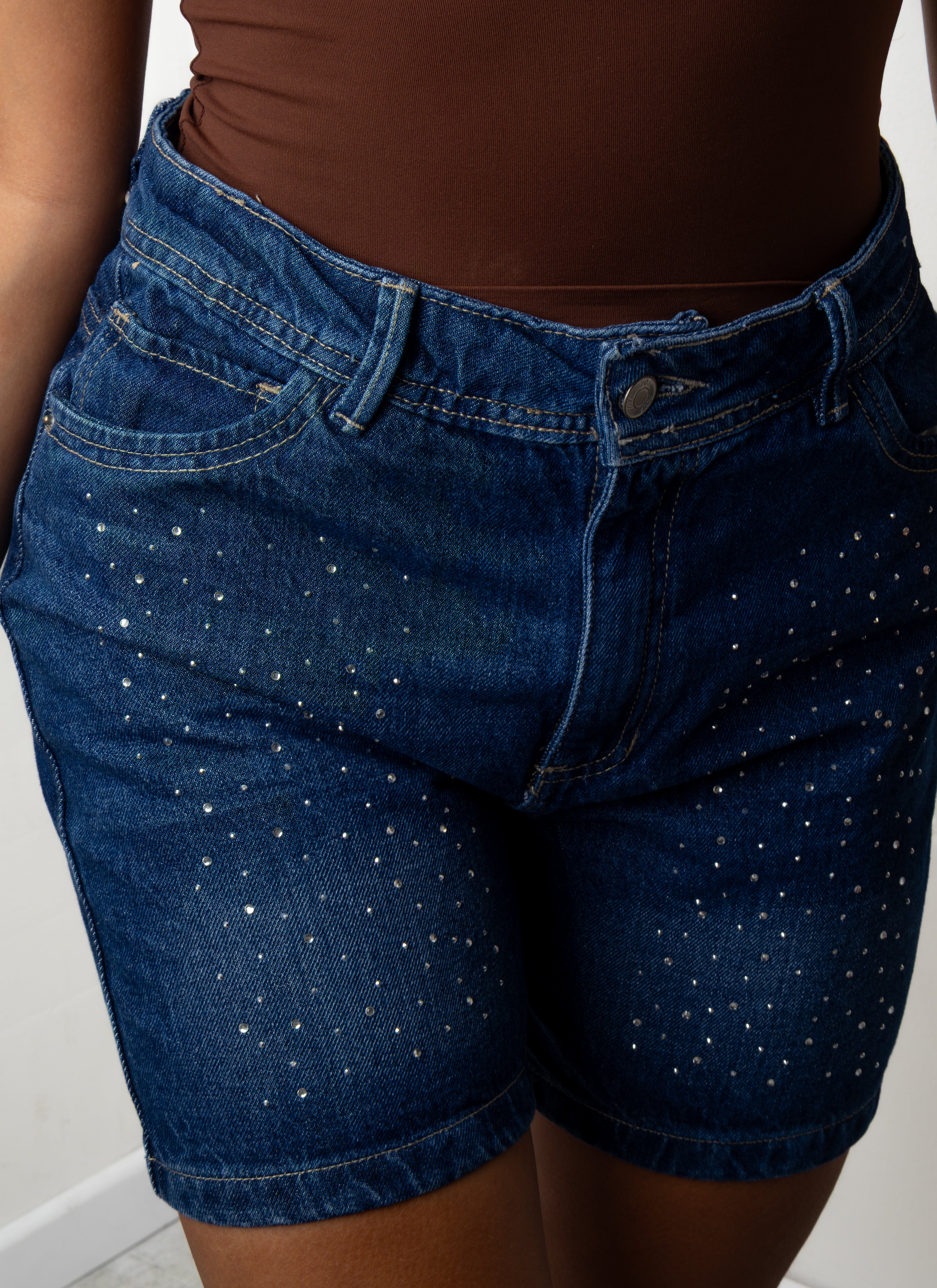 Plano detalle de mujer luciendo el Short Zoya de tiro alto en mezclilla azul oscuro decorado con pequeños apliques de pedrería brillante.